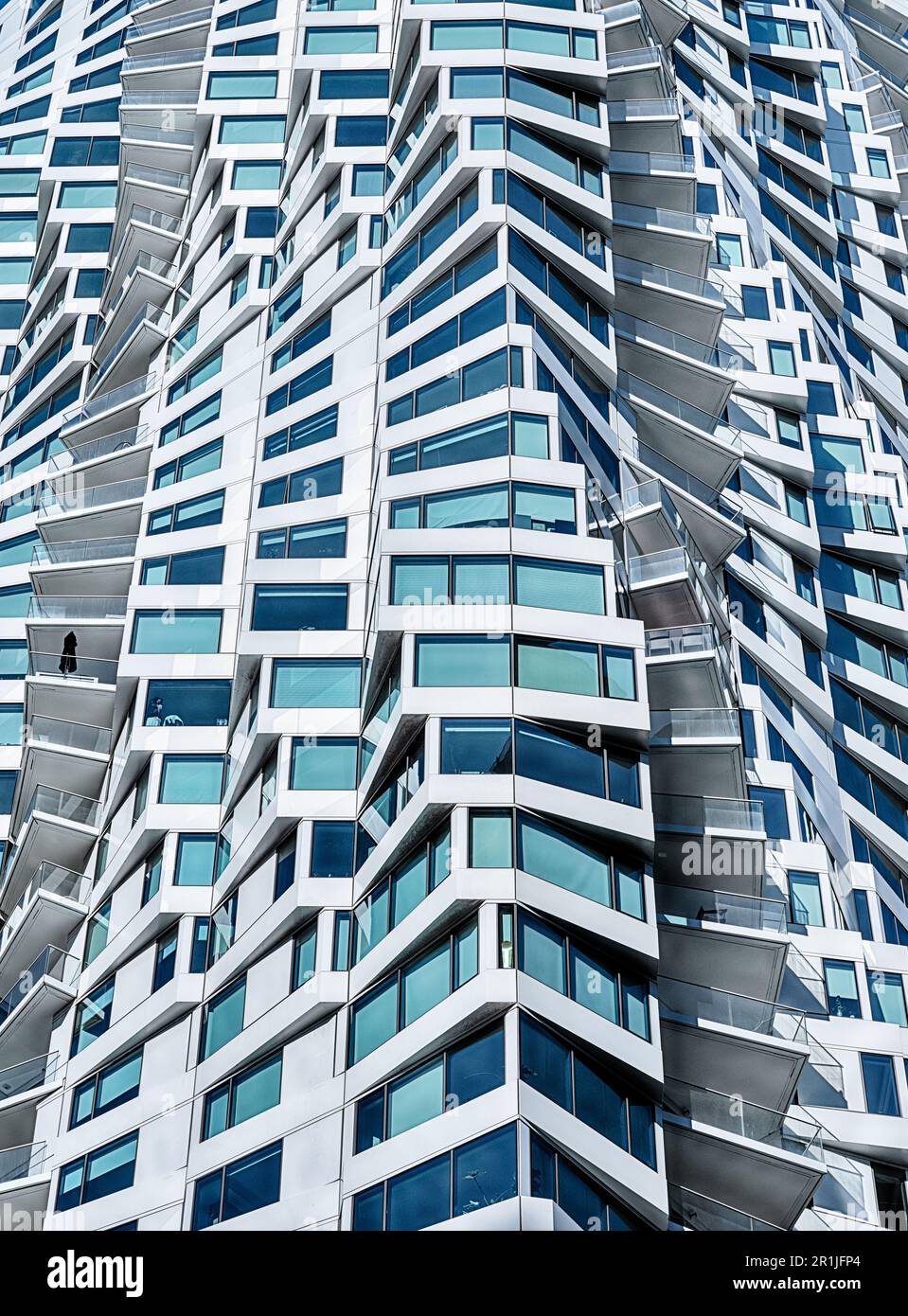 Il design esterno a spirale di un moderno edificio di appartamenti si traduce in un complesso sfondo di luce e ombra. Foto Stock