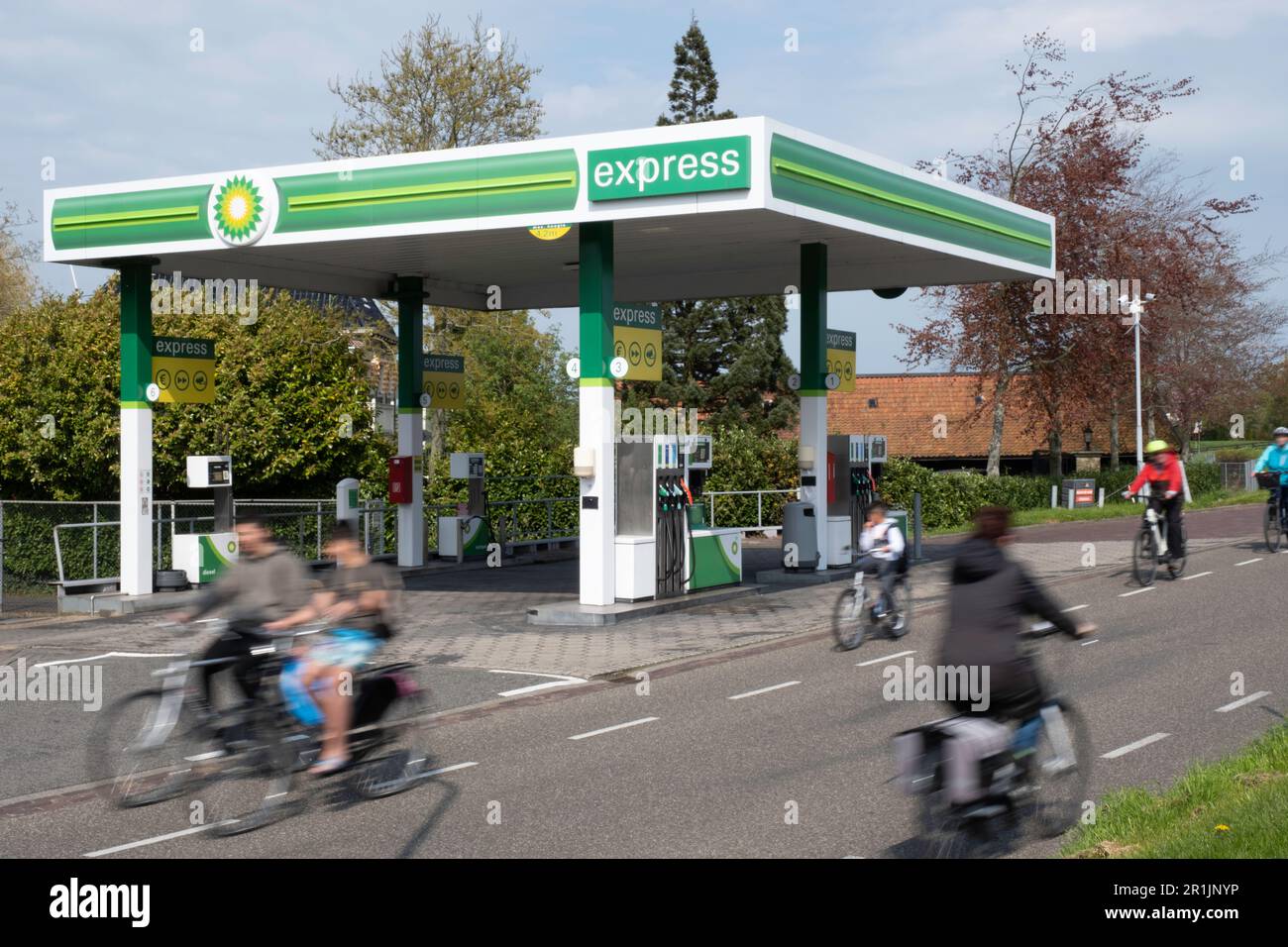 Stazione di servizio BP vuota lungo una strada con ciclista offuscata nel villaggio olandese di Lemmer nei Paesi Bassi. Transizione nella mobilità Foto Stock
