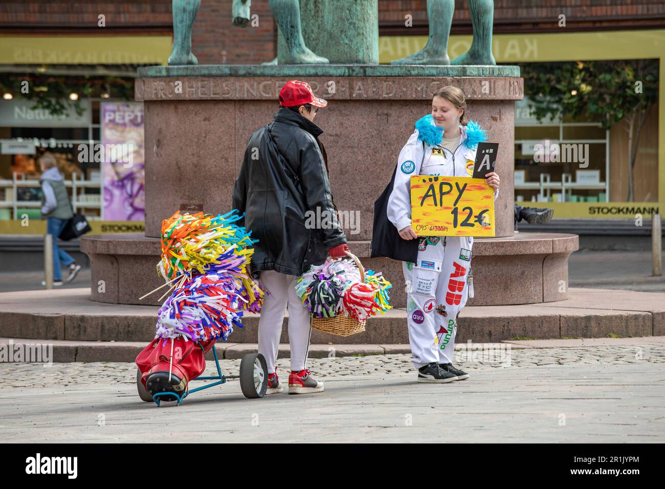 Il fornitore di accessori del giorno di maggio chiacchierando con lo studente di ingegneria che vende la rivista di umorismo a Helsinki, Finlandia Foto Stock