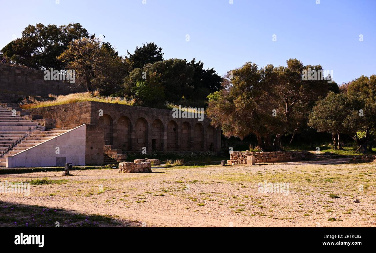 Parco archeologico con un antico edificio biblioteca con aperture ad arco e un antico anfiteatro odeon sull'isola di Rodi. Foto Stock