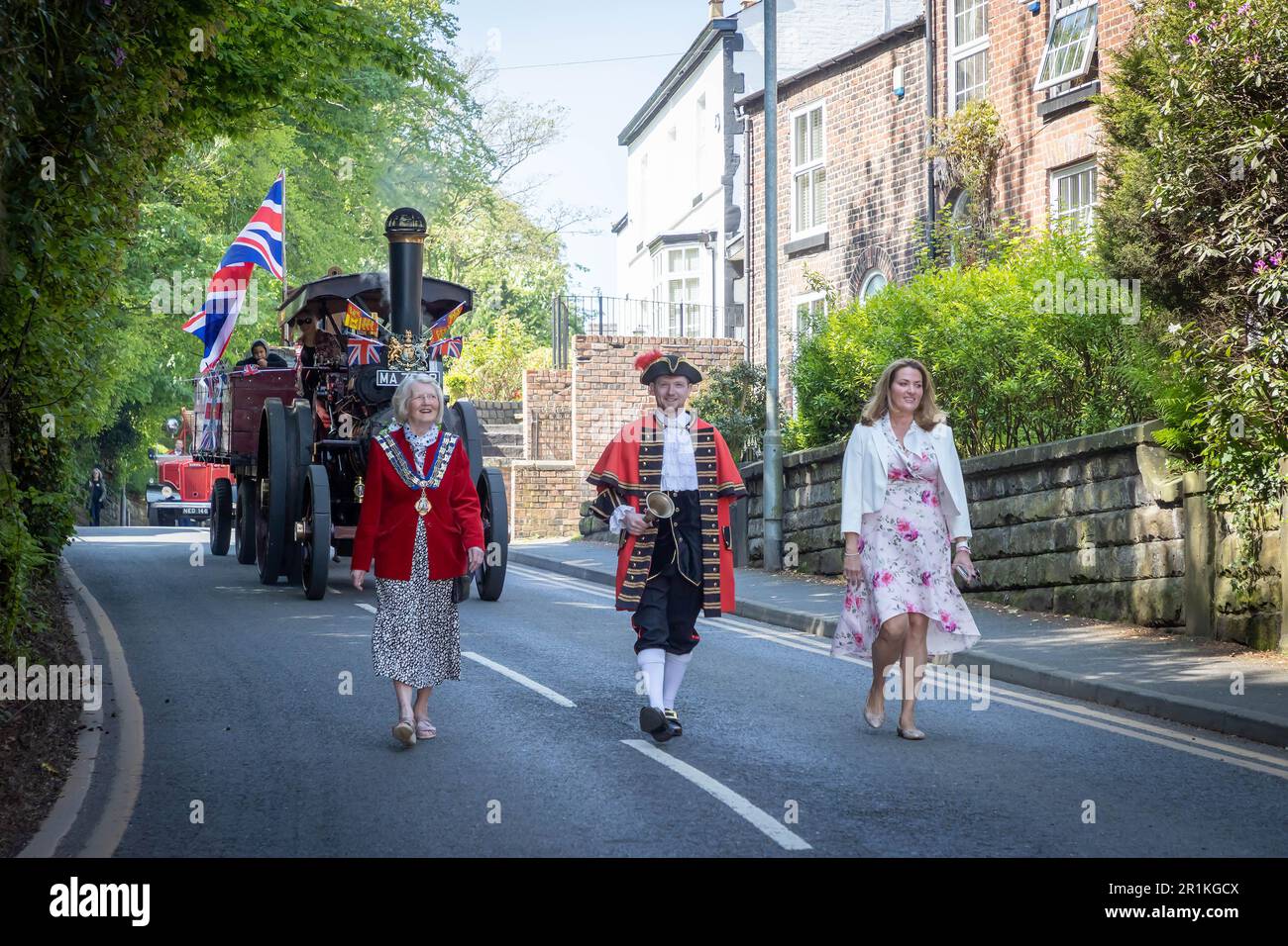 Lymm May Queen e Rose Queen 2023. Town Crier AJ Powell con i membri del Comitato guida la strada seguita da un motore di trazione Aveling & Porter Foto Stock