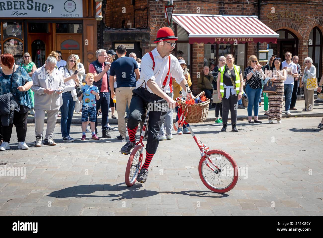 Lymm May Queen e Rose Queen 2023. Street performer a bordo di un monociclo con maniglia separata e ruota anteriore Foto Stock