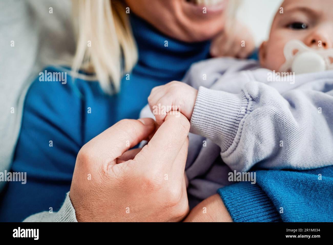 Primo piano della giovane madre che coccola il suo bambino neonato a casa - fuoco morbido sulla mano della mamma Foto Stock