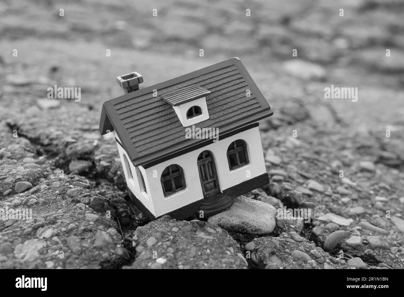 Modello di casa in asfalto fessurato. Terremoto disastro Foto Stock