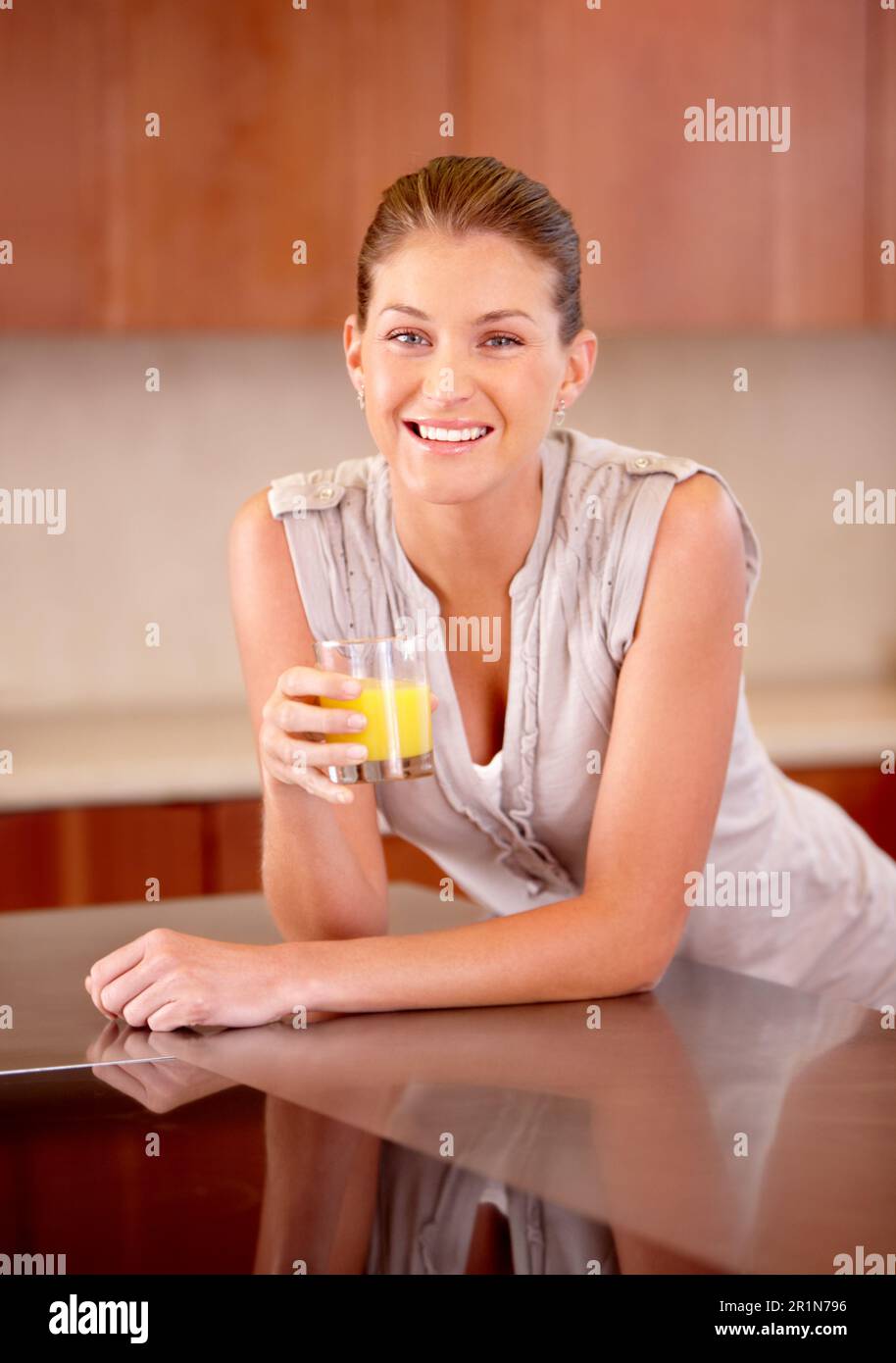 Donna felice, ritratto e succo d'arancia bere in casa per la vitamina C, benefici salutari e frullato colazione. Persona femminile, bicchiere e cocktail di frutta Foto Stock