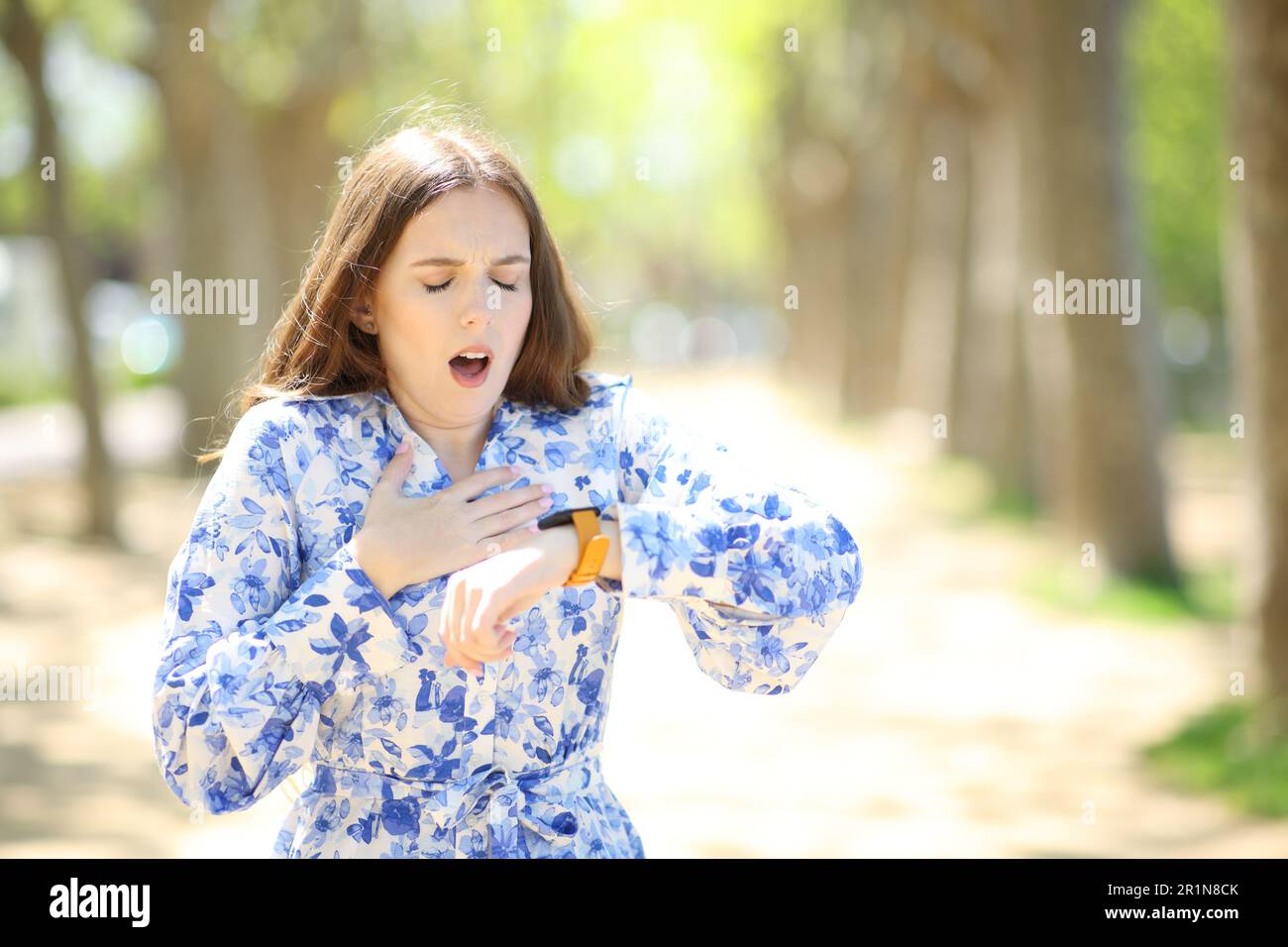 Donna asmatica che controlla le pulsazioni sullo smartwatch soffocando in un parco Foto Stock