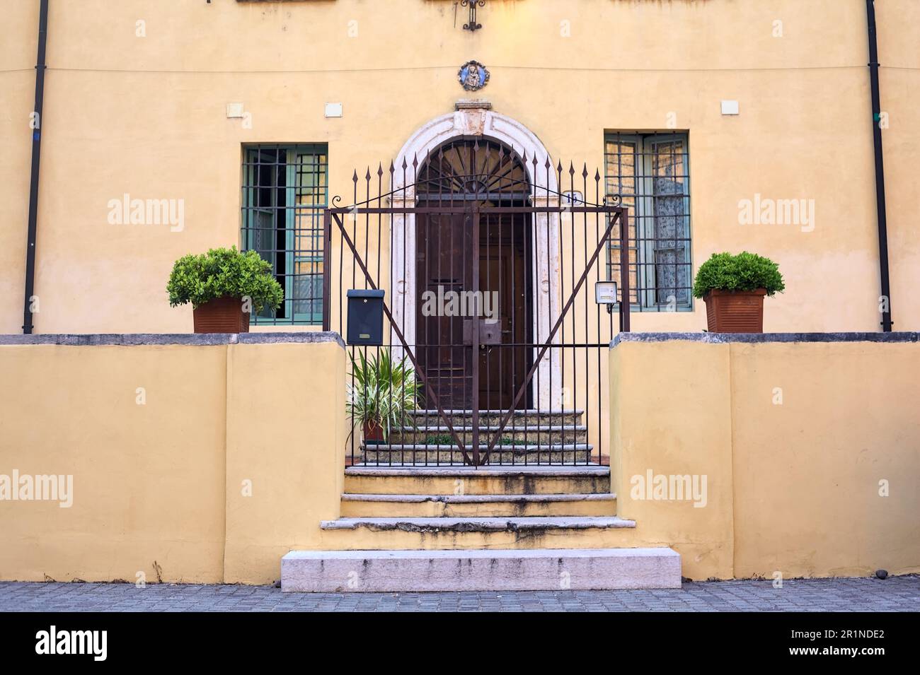 Porta dietro un cancello accanto a una scala in una piazza in una città italiana Foto Stock