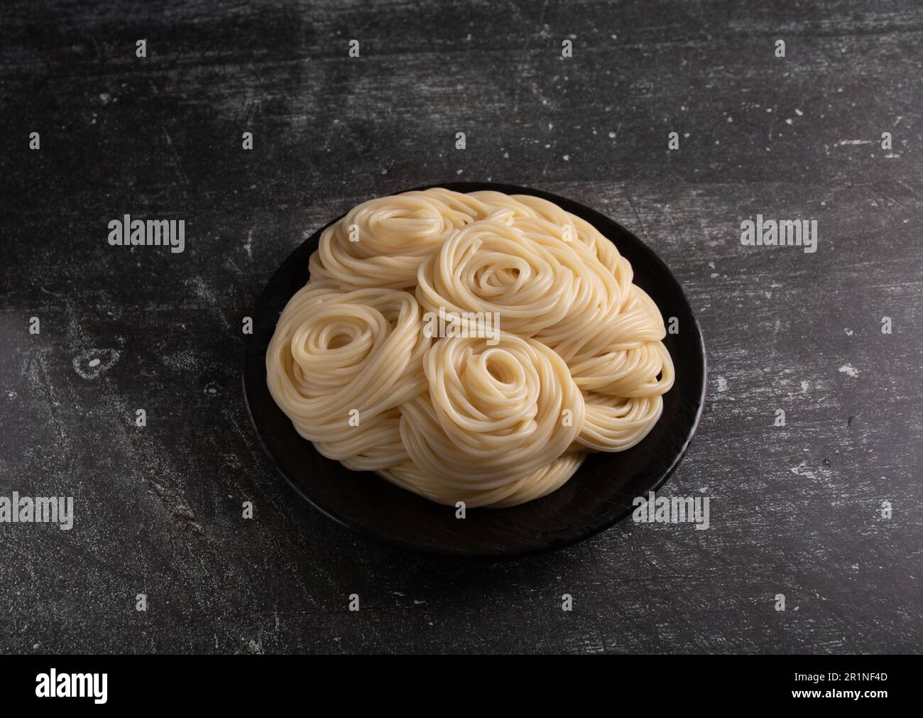 foto pasta bollita giacente in un piatto su uno sfondo scuro Foto Stock