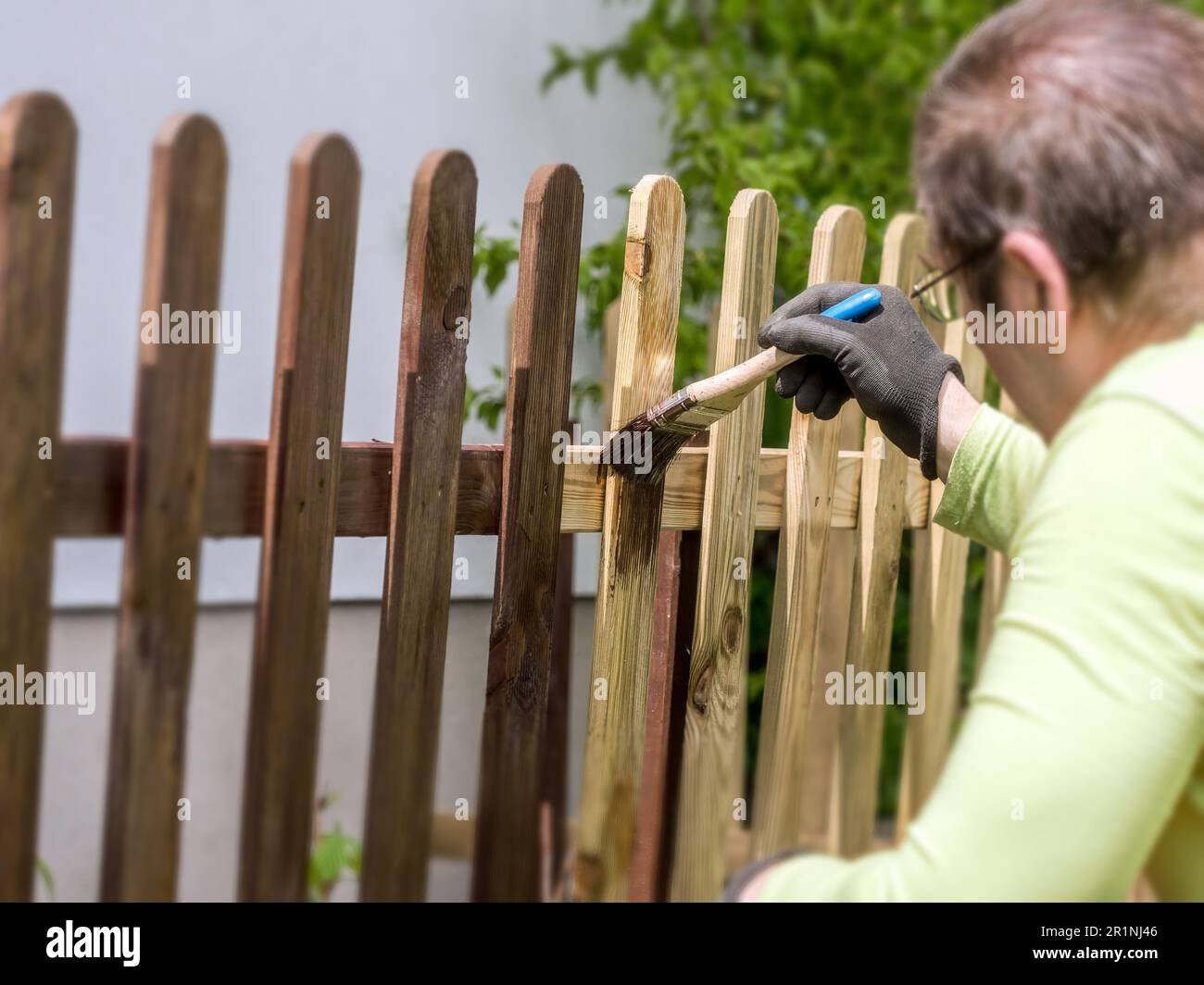 Casa proprietario verniciatura cortile recinto picket in legno con vernice marrone Foto Stock