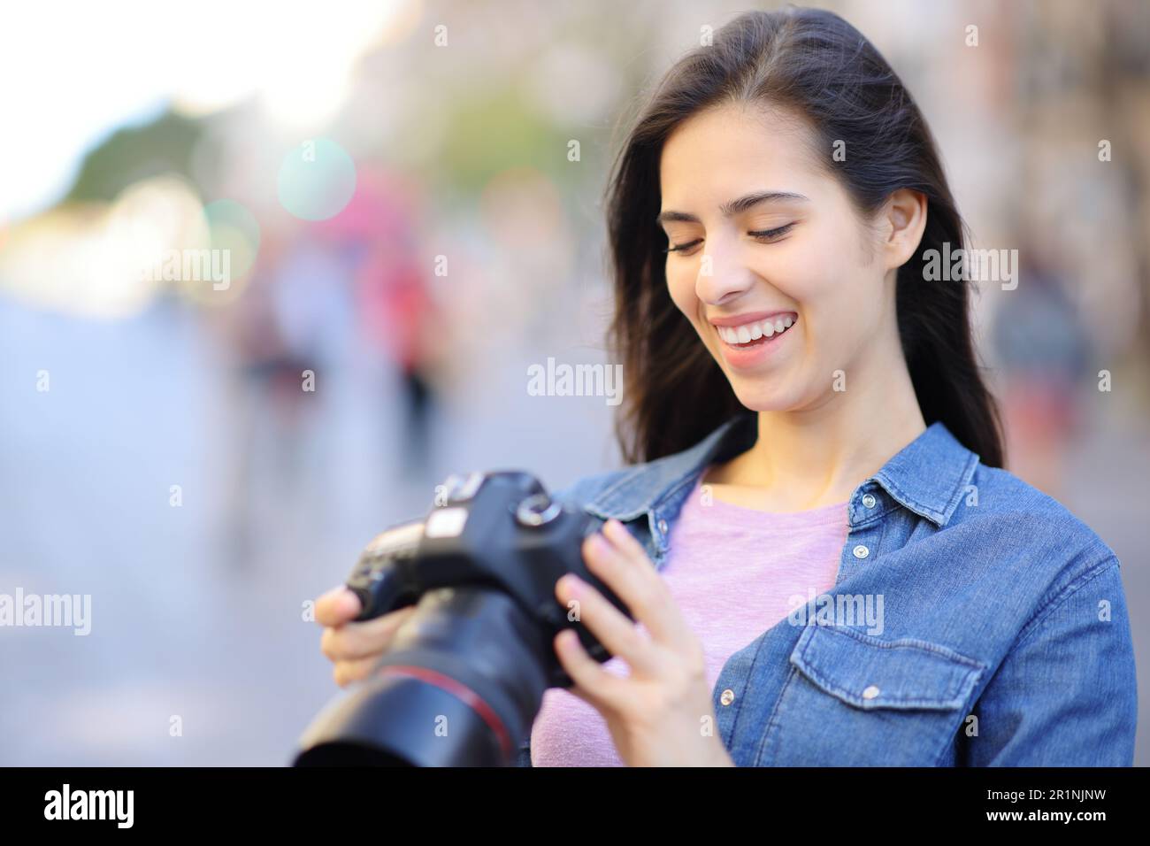 Felice fotografo che controlla le foto sulla fotocamera dslr in strada Foto Stock