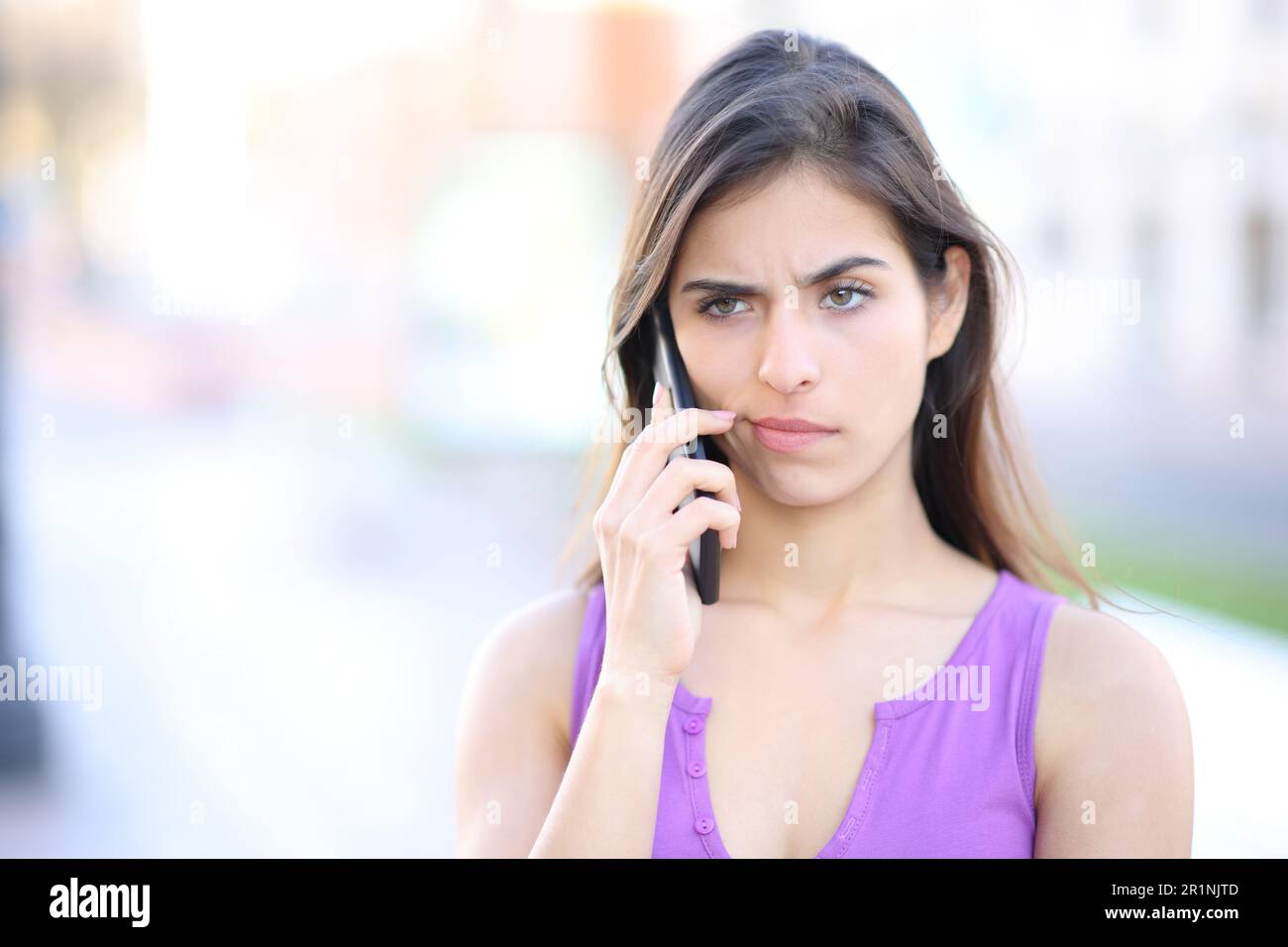 Donna sospetta che partecipa a una telefonata per strada Foto Stock