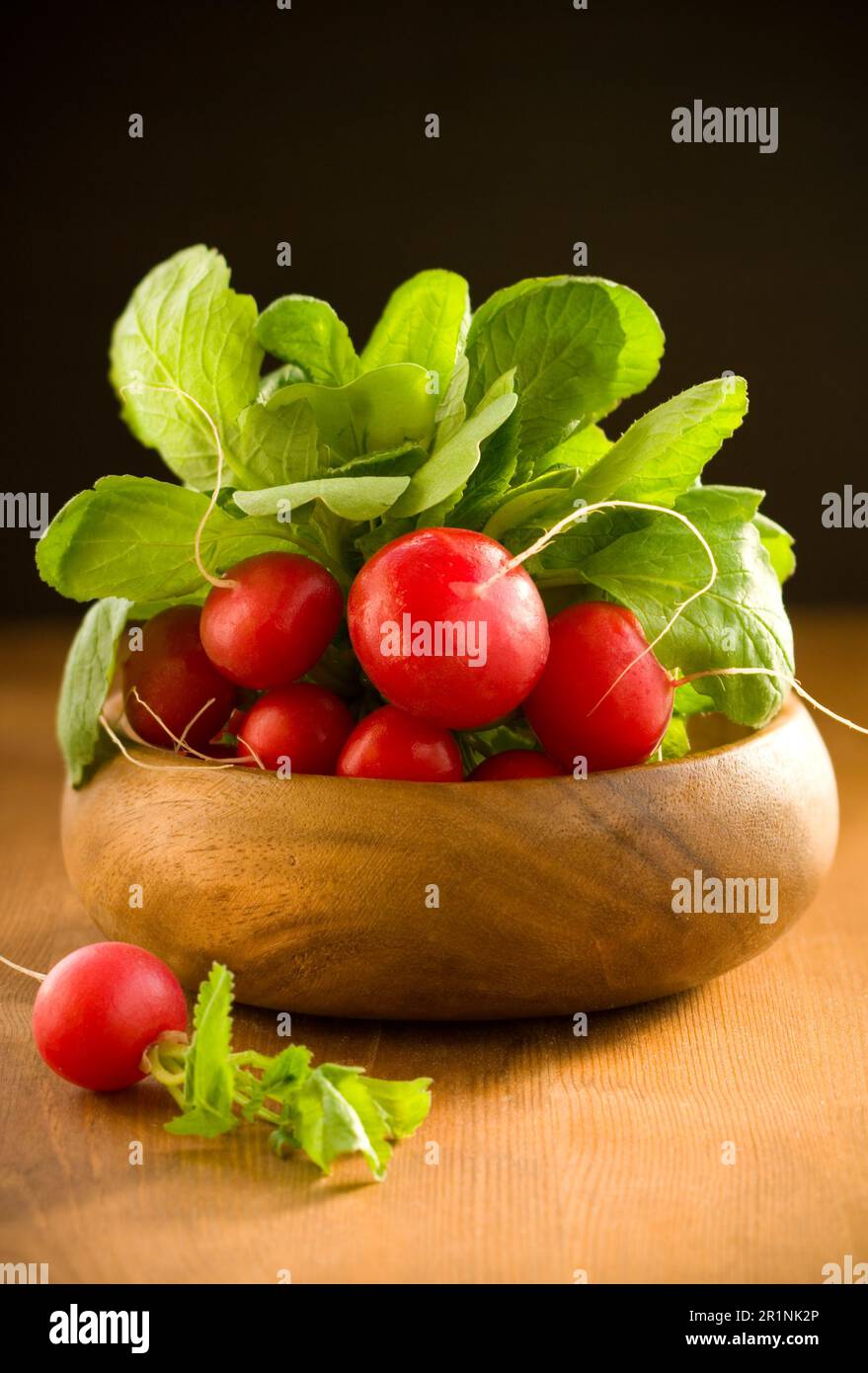 Un mazzetto di ravanelli freschi in una ciotola di legno Foto Stock