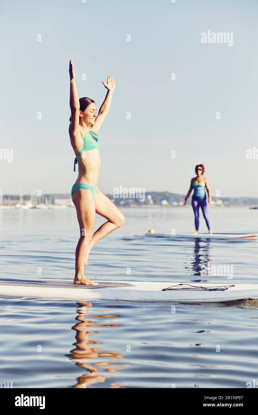 Due donne che fanno yoga sulle tavole SUP la mattina presto Foto Stock