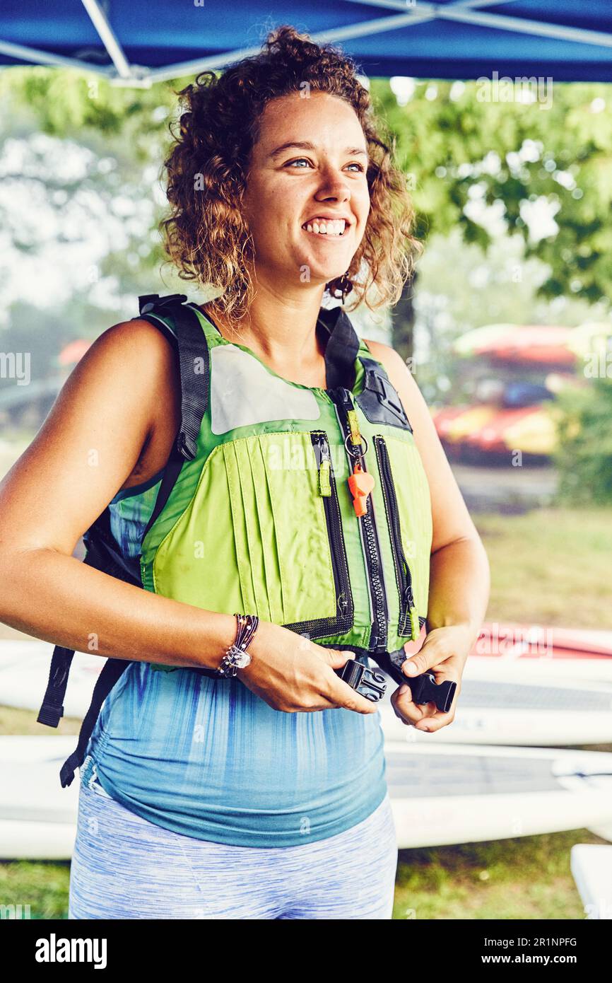 La giovane donna indossa il giubbotto salvagente in preparazione al viaggio in kayak Foto Stock