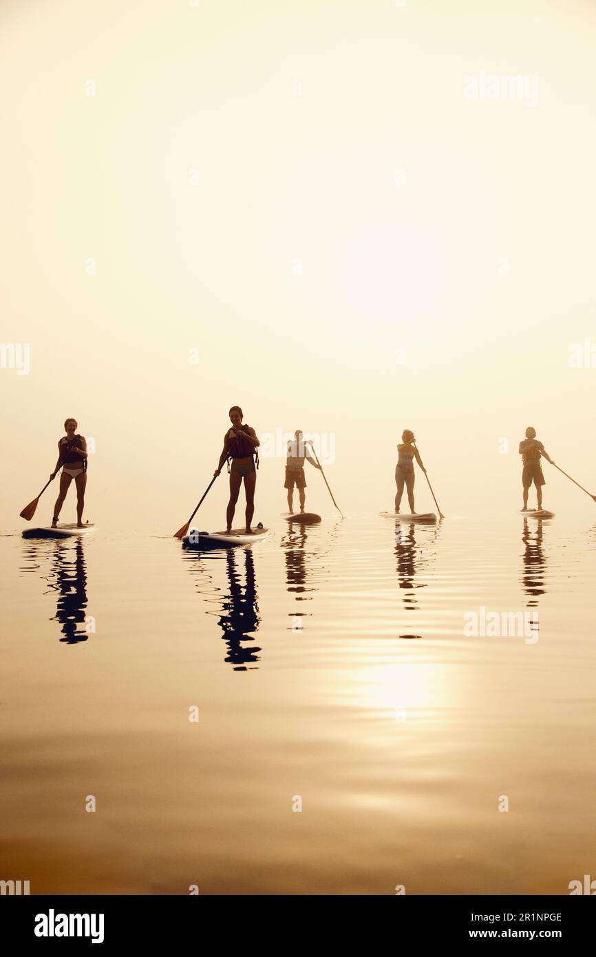 Un gruppo di pagaianti in standup su una mattina nebbiosa all'alba Foto Stock