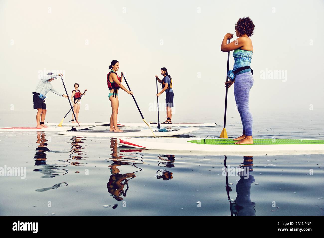 Un gruppo di pagaianti in standup su una mattina nebbiosa all'alba Foto Stock