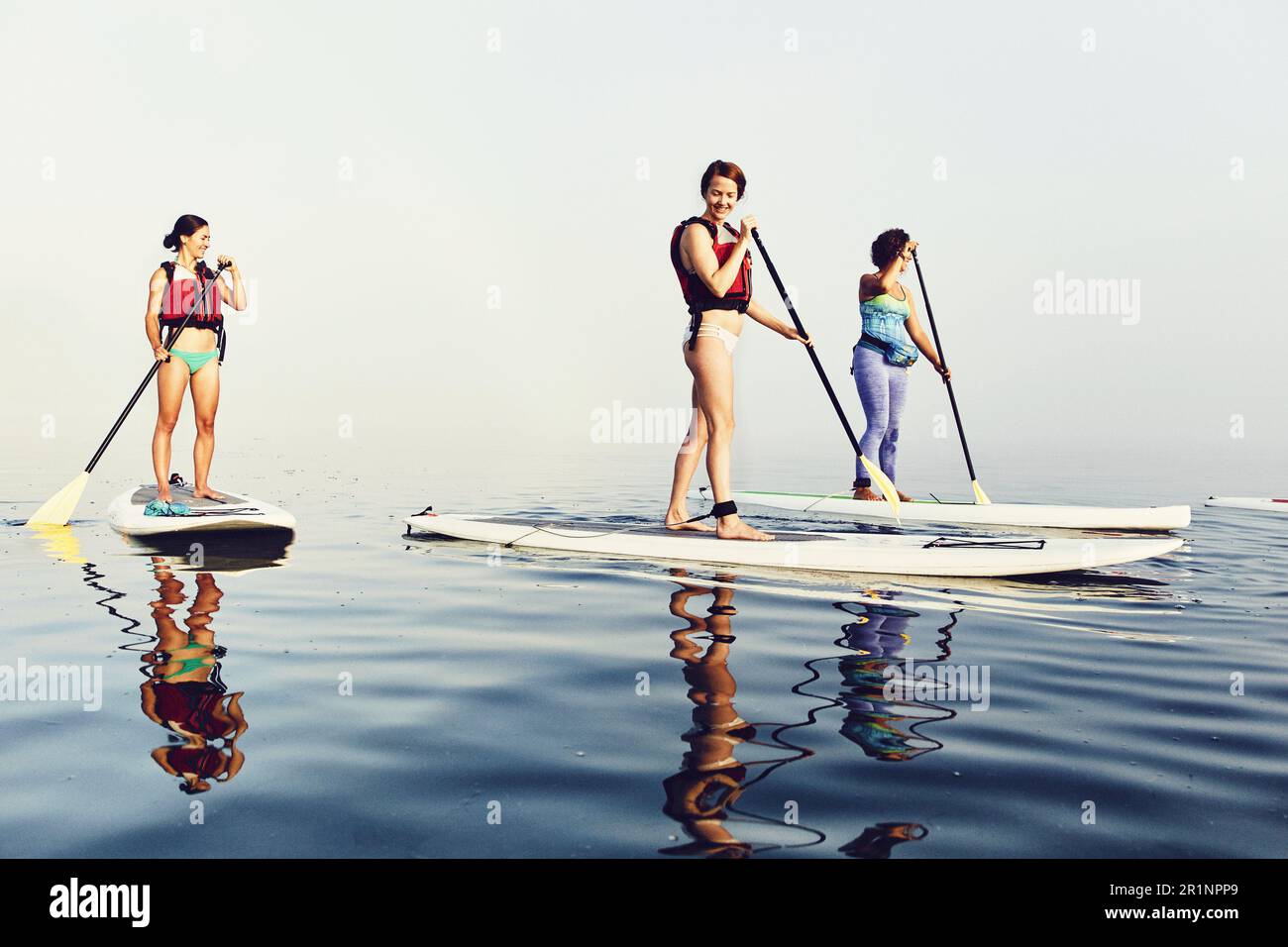Un gruppo di standup paddle boarder in una mattina nebbia a casco Bay Foto Stock