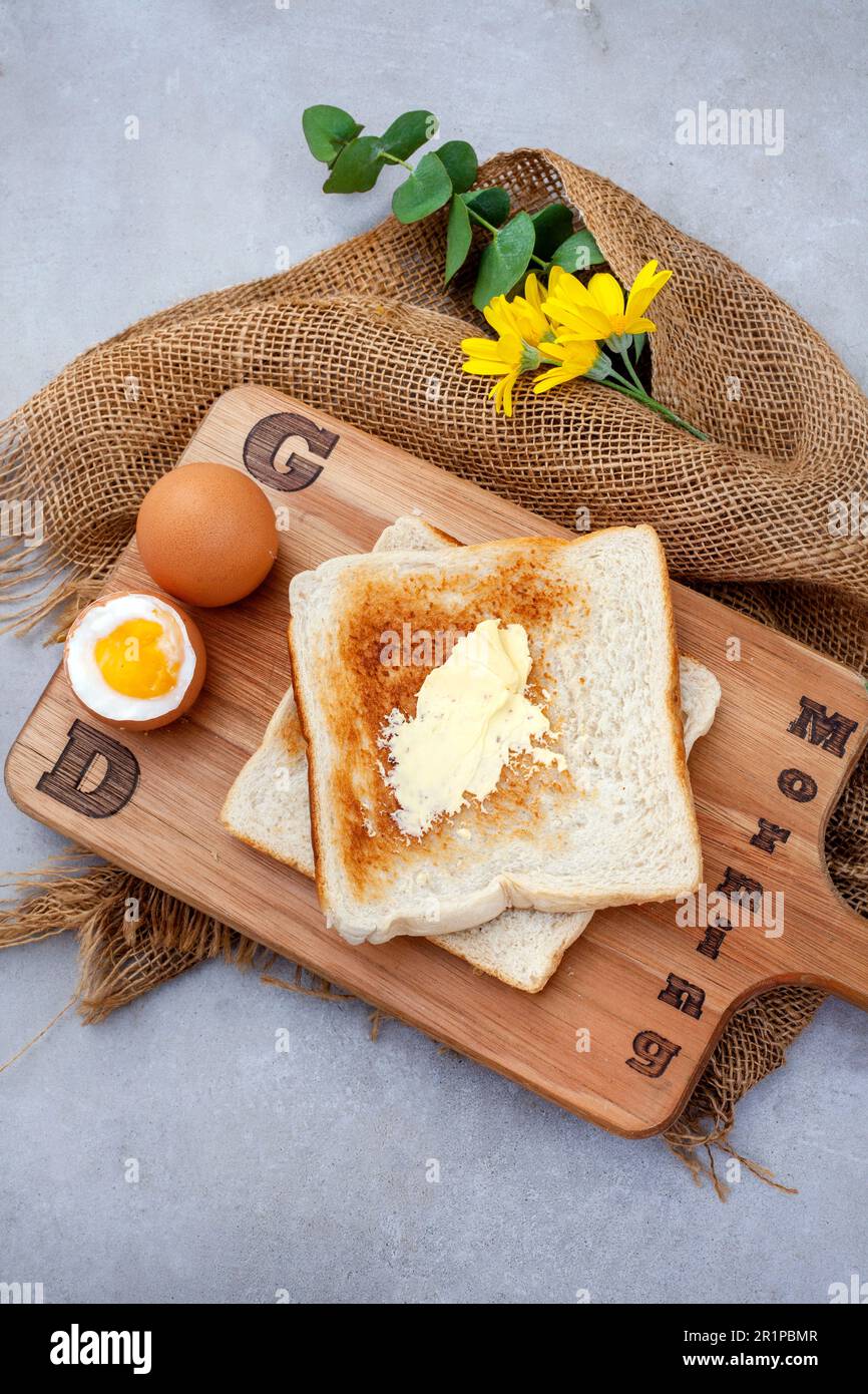 Buona colazione. Uova bollite e toast su asse di legno con testo. Rustico sul grigio Foto Stock