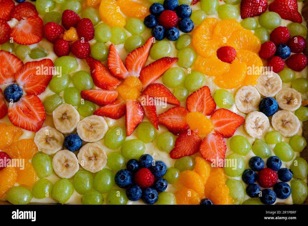 Torta sormontata con vari frutti a forma di fiori. Foto Stock