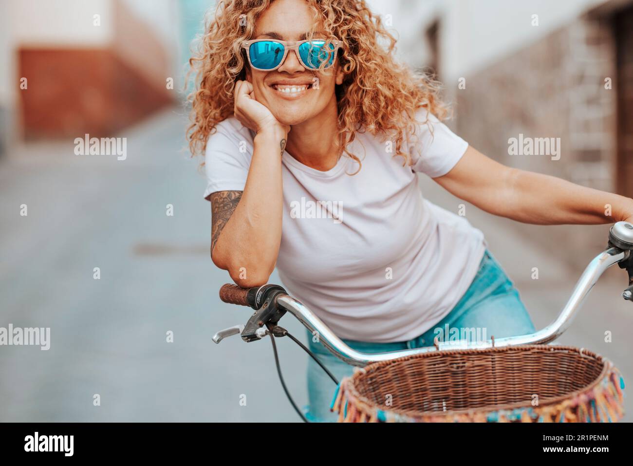 Ritratto frontale di bella giovane donna sorridente alla macchina fotografica e indossando occhiali da sole. Bicicletta da corsa per uno stile di vita sano e attivo e la scelta dell'ambiente di trasporto verde. Donna attraente per il tempo libero all'aperto Foto Stock