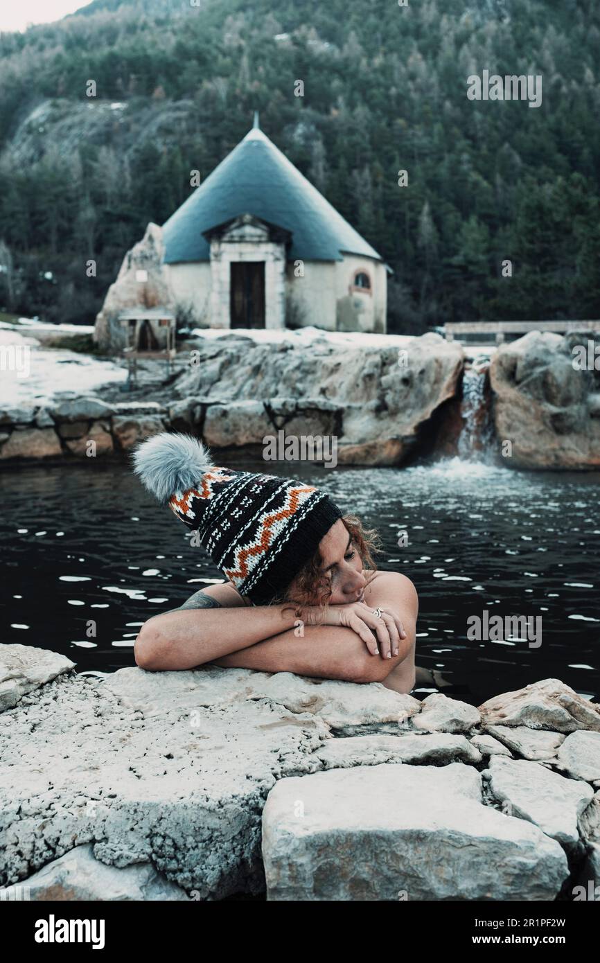 Rilassato turista femminile godere di caldo vulcanico naturale piscina termale acqua attività termale con cappello d'inverno. Concetto di benessere e cura della pelle del corpo. Natura stile di vita sano. Donna che si gode una giornata di relax Foto Stock