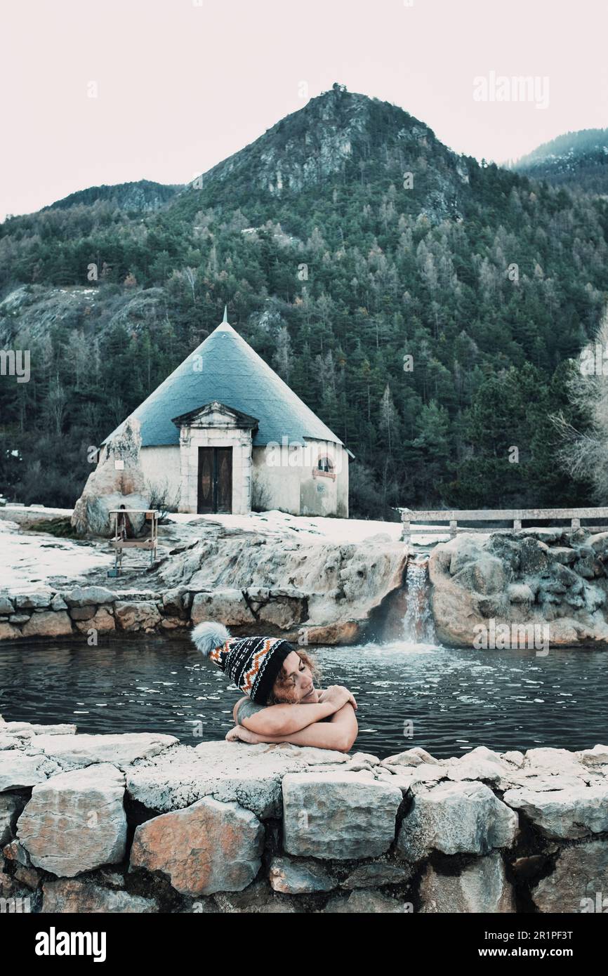 Una donna si rilassa nella piscina termale naturale nella stagione invernale in un luogo panoramico di montagna. Natura e cura della pelle sana. Benessere e benessere all'aperto attività di svago. Donne all'aperto Foto Stock