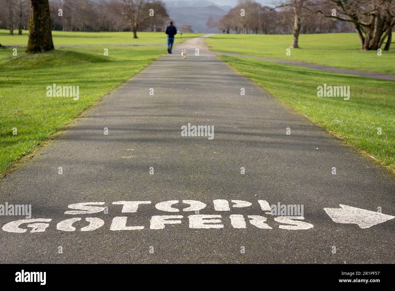 Uomo con un cane che cammina sul vicolo del campo da golf con il testo di avvertimento di Stop golfers al Killarney Golf and Fishing Club, County Kerry, Irlanda Foto Stock
