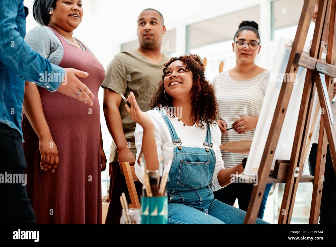 Che ne pensi. una giovane donna attraente seduta e che spiega le sue opere d'arte ai suoi amici durante una lezione d'arte. Foto Stock