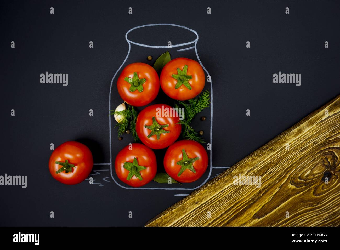 Una banca è disegnata con il gesso su uno sfondo nero. Ci sono pomodori rossi maturi nel vaso. Foto creativa di inscatolamento di pomodoro. Foto Stock