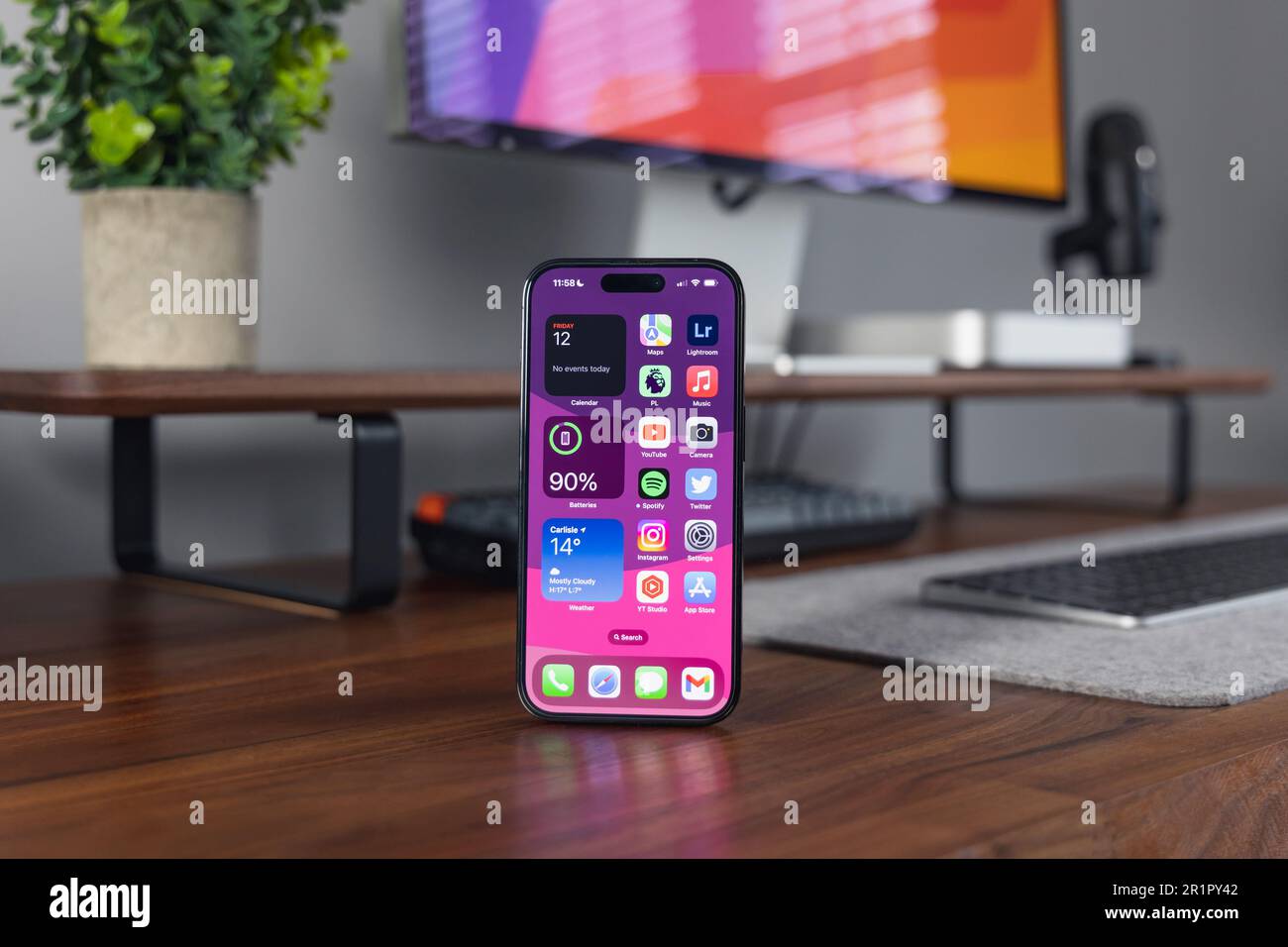 LONDRA - 12 MAGGIO 2023: Apple iPhone 14 Pro con sfondo in legno home Office configurazione minima della scrivania Foto Stock