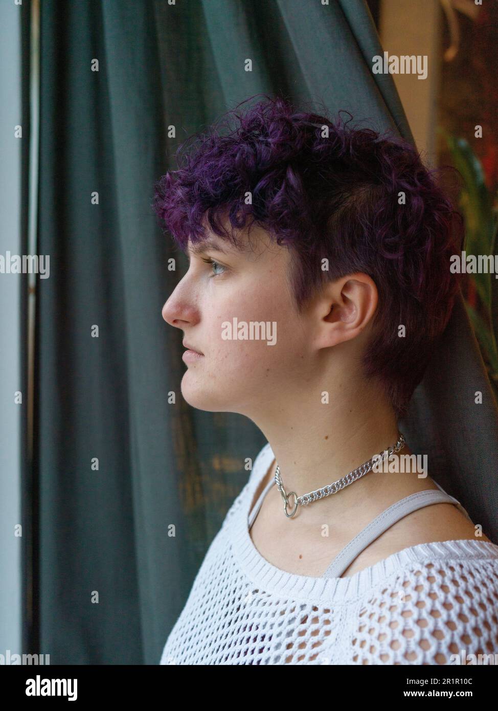 Persona non binaria alla finestra Foto Stock