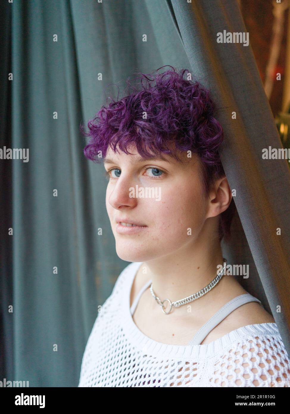 Persona non binaria alla finestra Foto Stock