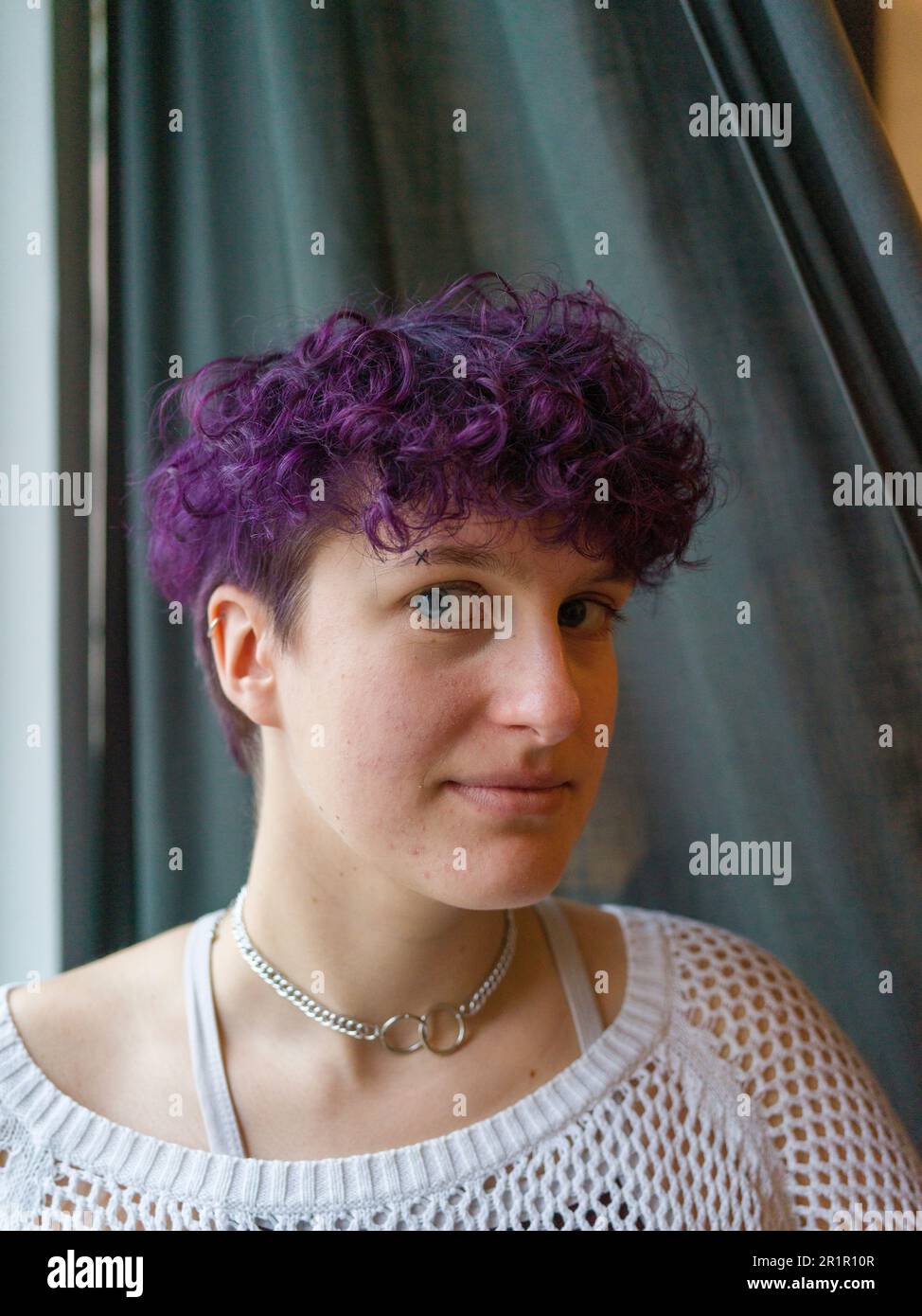 Persona non binaria alla finestra Foto Stock