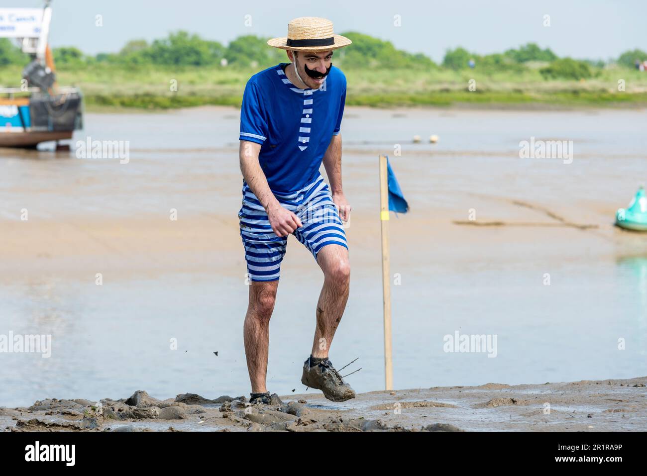 Joe Bayley in costume francese finendo secondo nella Maldon Mud Race a Maldon, Essex, Regno Unito, nel fango del fiume Blackwater Foto Stock