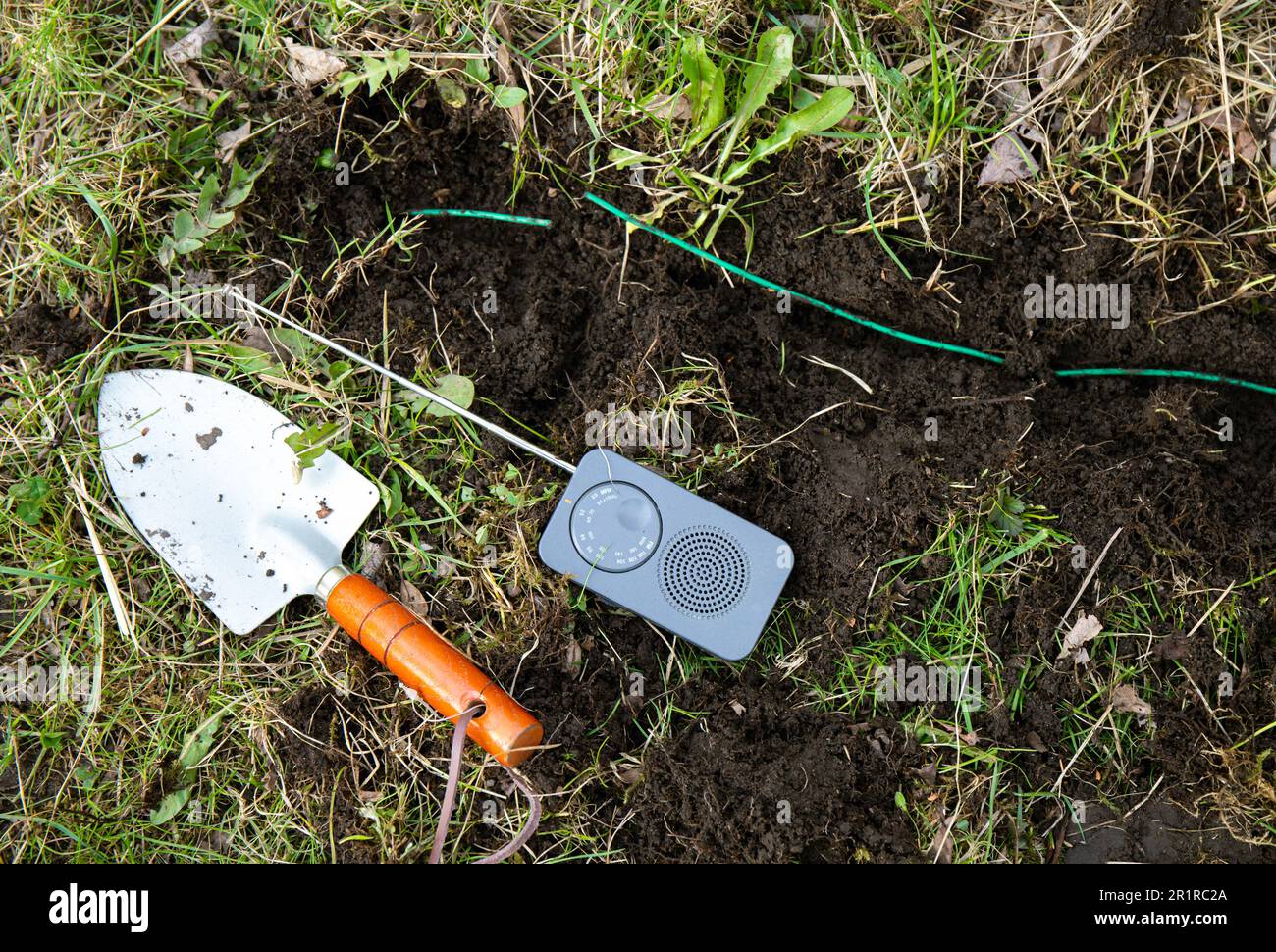 Come individuare un'interruzione nel cavo perimetrale di un rasaerba robotizzato? Utilizzando un piccolo segnale di interferenza radio AM alimentato a batteria per individuare la parte rotta . Foto Stock