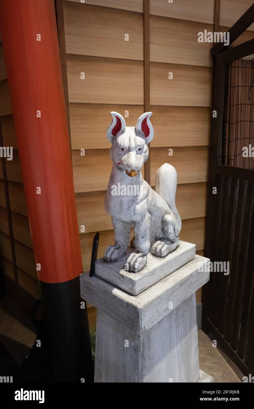 Statua color bronzo di una volpe giapponese di Kitsune con orecchie rosse Foto Stock