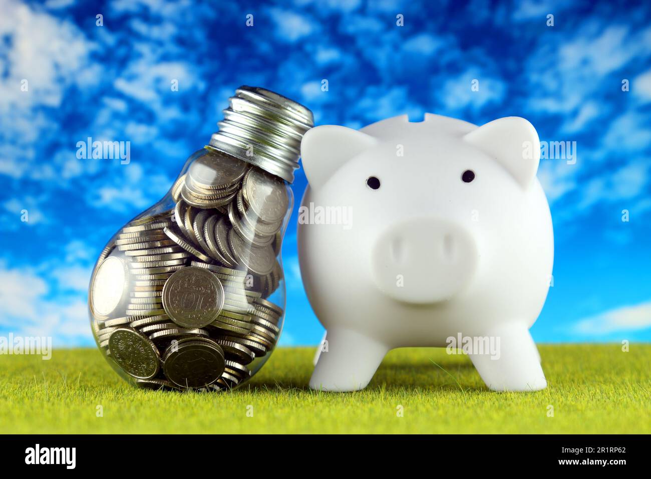 Monete all'interno della lampadina e del banco di porcellini. Eco-verde energia rinnovabile concetto. I prezzi dell'elettricità, il risparmio energetico in famiglia. Foto Stock