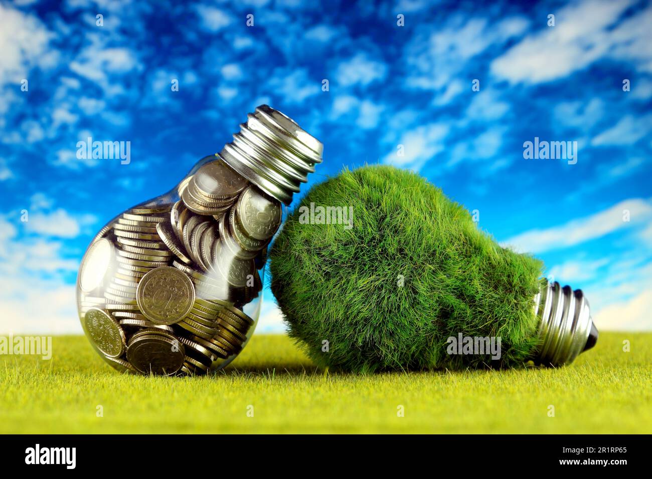 Monete all'interno della lampadina e lampadina verde eco con erba. Concetto di energia rinnovabile. I prezzi dell'elettricità, il risparmio energetico in famiglia. Foto Stock