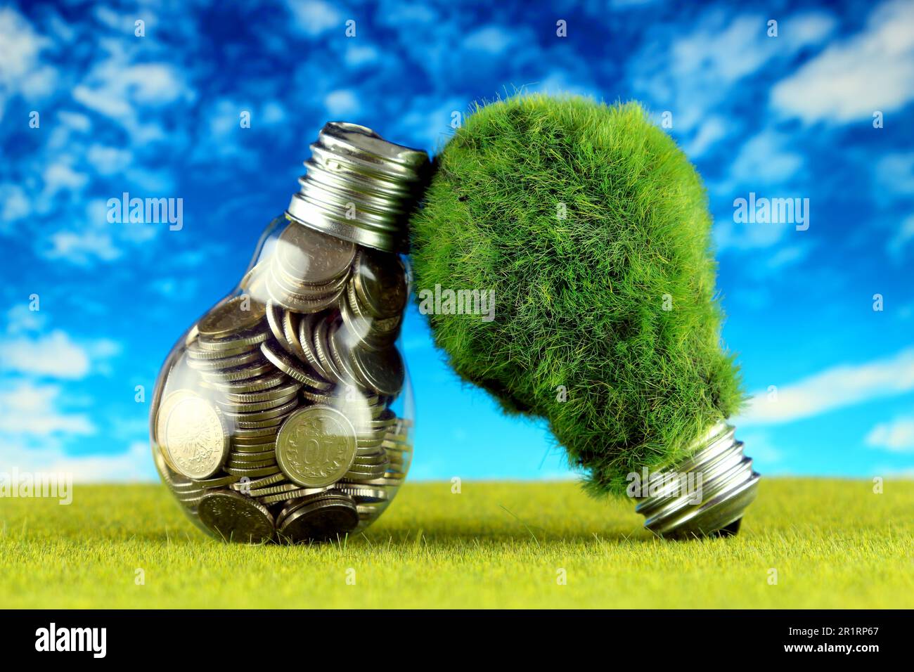 Monete all'interno della lampadina e lampadina verde eco con erba. Concetto di energia rinnovabile. I prezzi dell'elettricità, il risparmio energetico in famiglia. Foto Stock