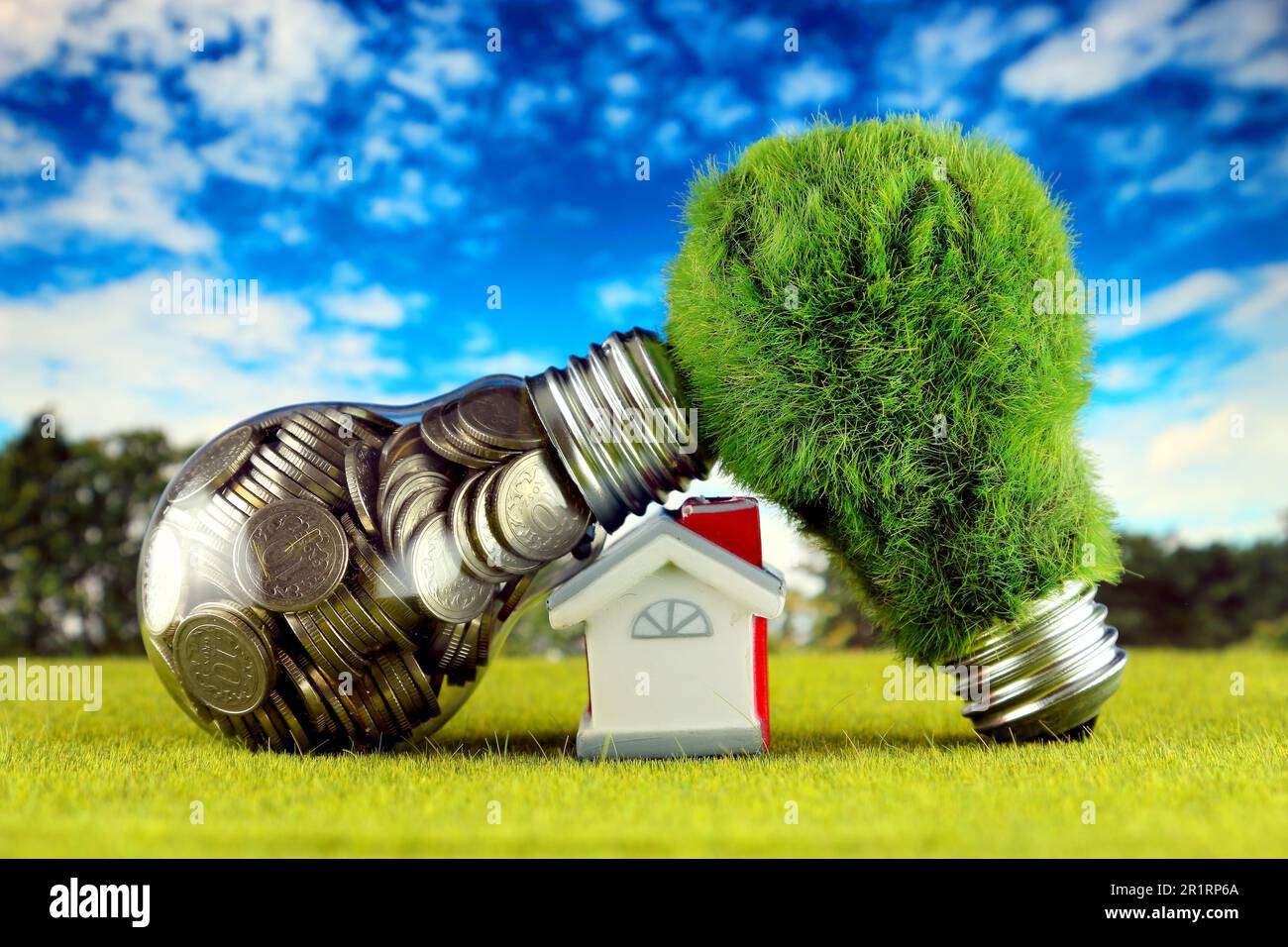 Monete all'interno della lampadina, lampadina verde eco con erba e casa in miniatura. Concetto di energia rinnovabile. I prezzi dell'elettricità, il risparmio energetico nelle ore Foto Stock