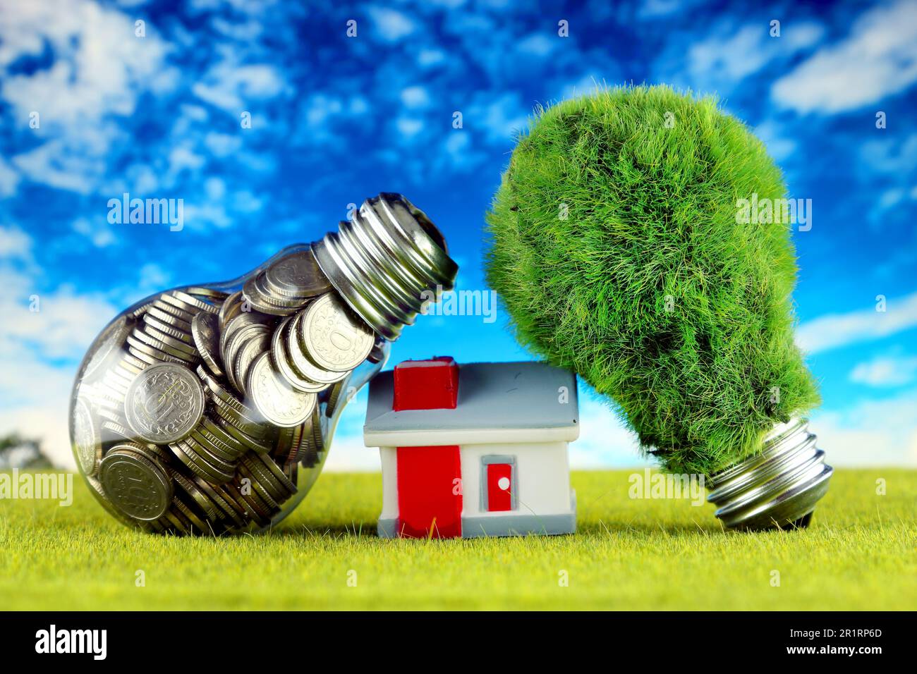 Monete all'interno della lampadina, lampadina verde eco con erba e casa in miniatura. Concetto di energia rinnovabile. I prezzi dell'elettricità, il risparmio energetico nelle ore Foto Stock