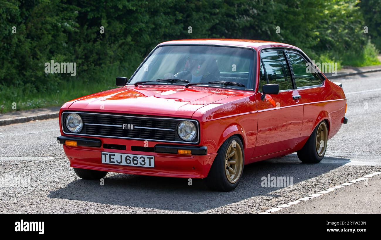 Stoke Goldington, Northants, Regno Unito - Maggio 14th 2023. 1979 ROSSO FORD ESCORT 1600 SPORT auto classica guida attraverso un villaggio inglese Foto Stock