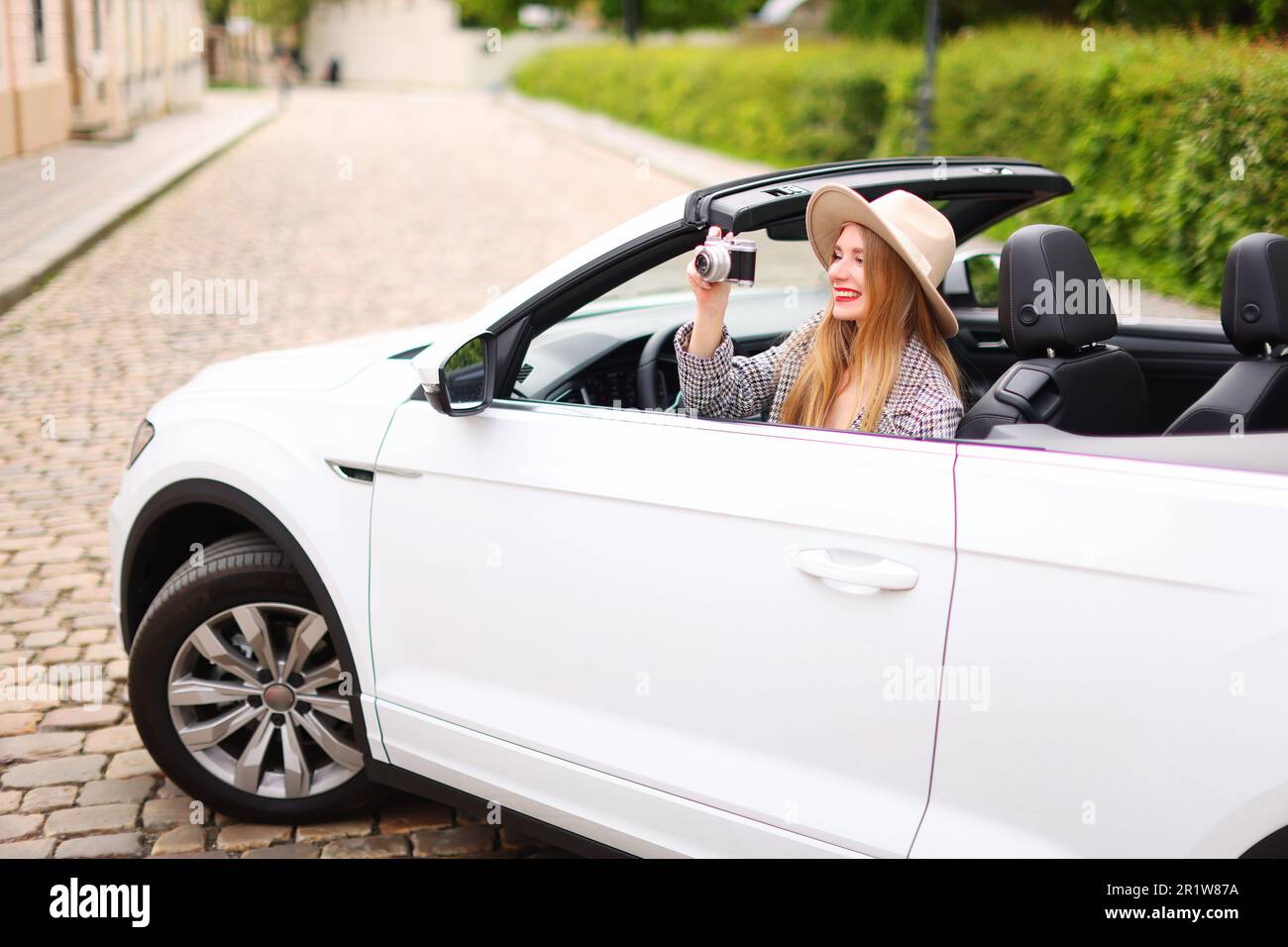 tempo libero, viaggio, concetto di viaggio - ragazza felice che guida in cabriolet auto e scattare foto da telecamera Foto Stock