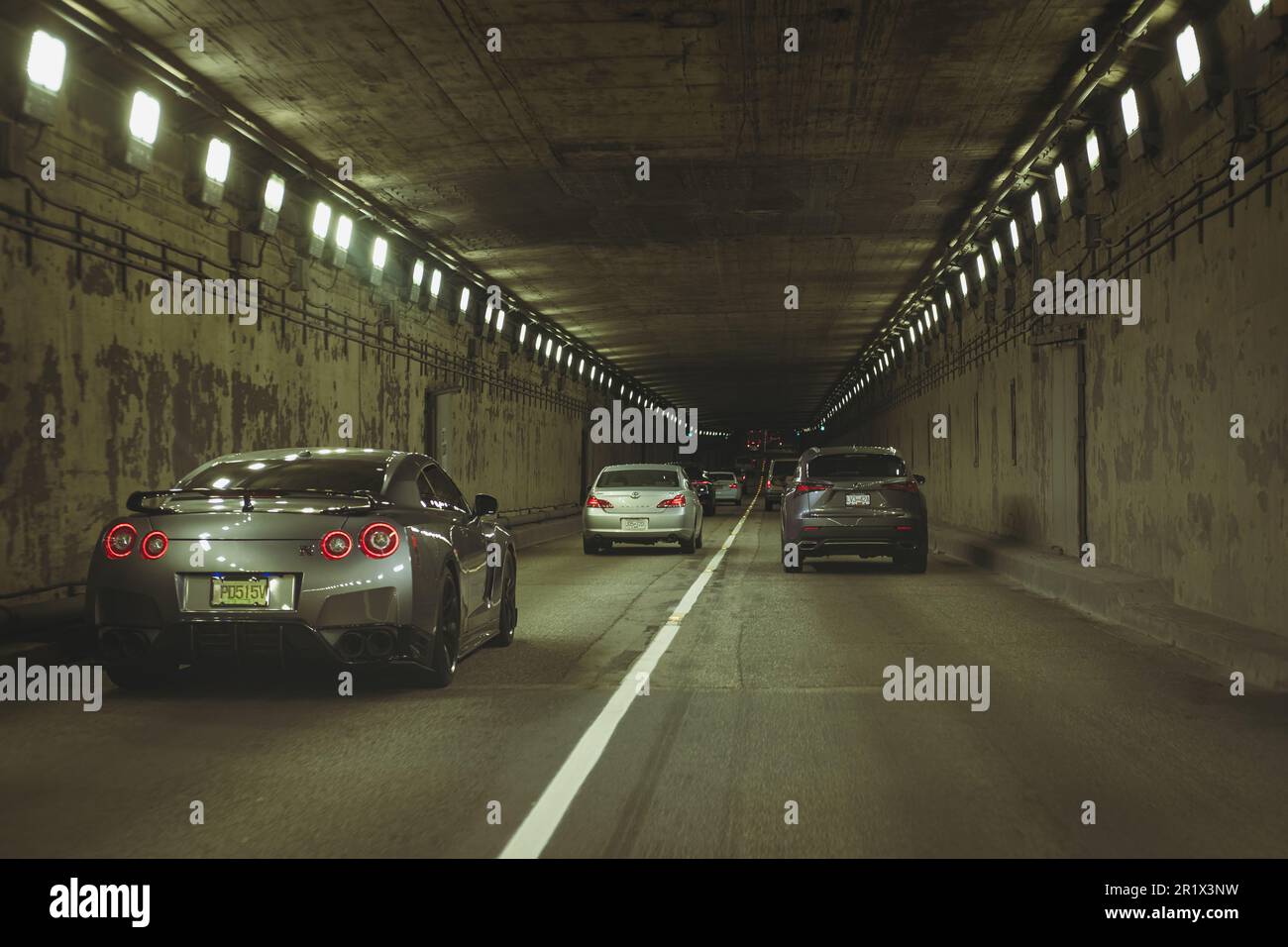 L'auto passa attraverso il punto di vista del tunnel. Luce tunnel sfocata durante la guida. Interno di un tunnel urbano con traffico. Messa a fuoco selettiva, nobod Foto Stock