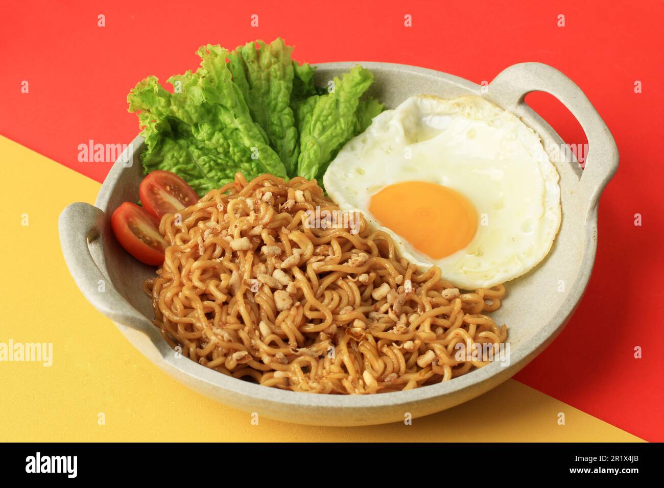 Indomie Goreng, popolare indonesiano Instant Noodle con sole uova lato su sfondo rosso e giallo Foto Stock