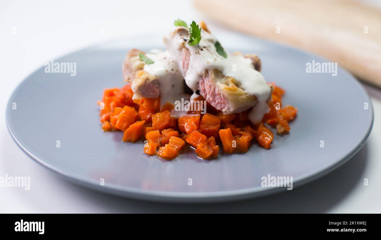 Lombo di maiale cotto con carota e salsa di formaggio. Foto Stock