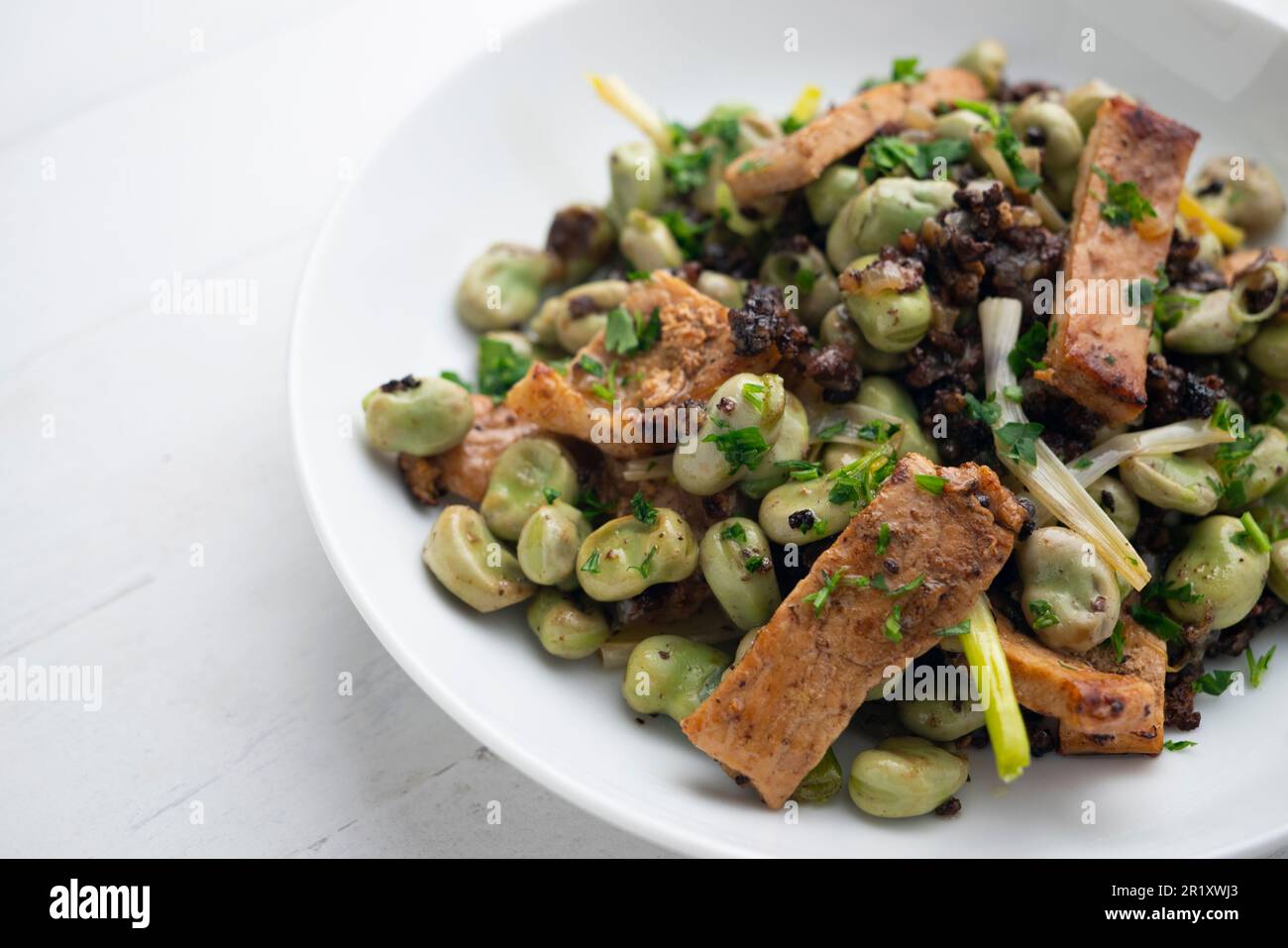 Lombo di maiale saltato con fagiolini verdi e budino nero. Foto Stock