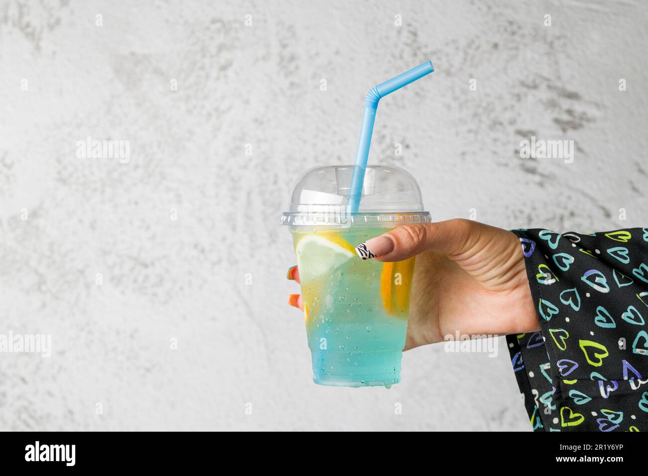 Donna che tiene la bolla tè con limonata di fronte al muro di pietra grigia Foto Stock
