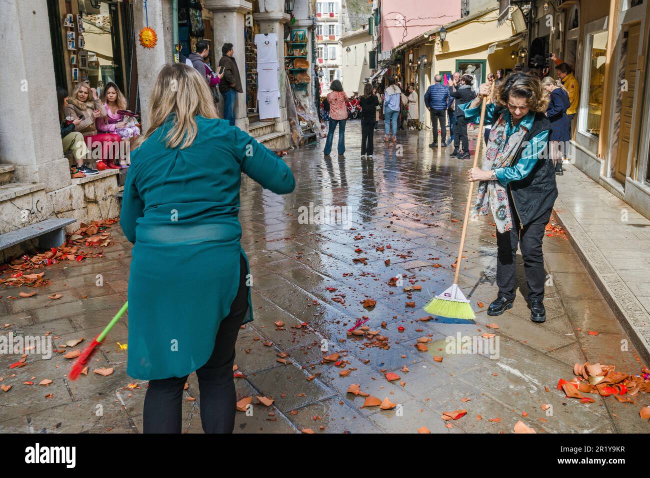 Proprietari di negozi, dipendenti che raccolgono barbatuffoli di vasi di ceramica rotti sulla strada prima di marching band torna, Sabato Santo, nella sezione di Campiello (Città Vecchia di Corfù), nella città di Corfù, isola di Corfù, Grecia Foto Stock