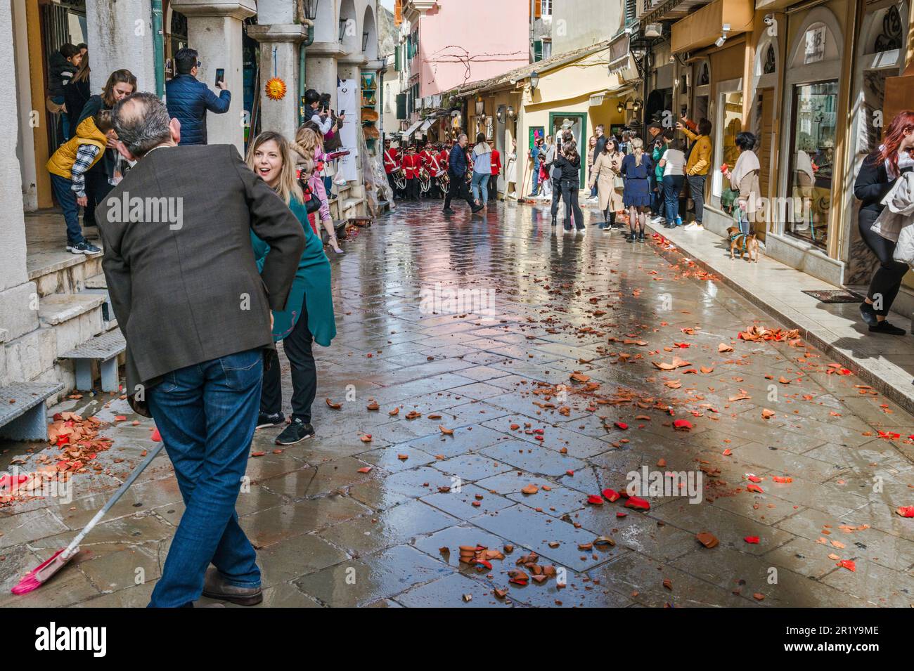 Proprietari di negozi, dipendenti che raccolgono barbatuffoli di vasi di ceramica rotti sulla strada prima di marching band torna, Sabato Santo, nella sezione di Campiello (Città Vecchia di Corfù), nella città di Corfù, isola di Corfù, Grecia Foto Stock